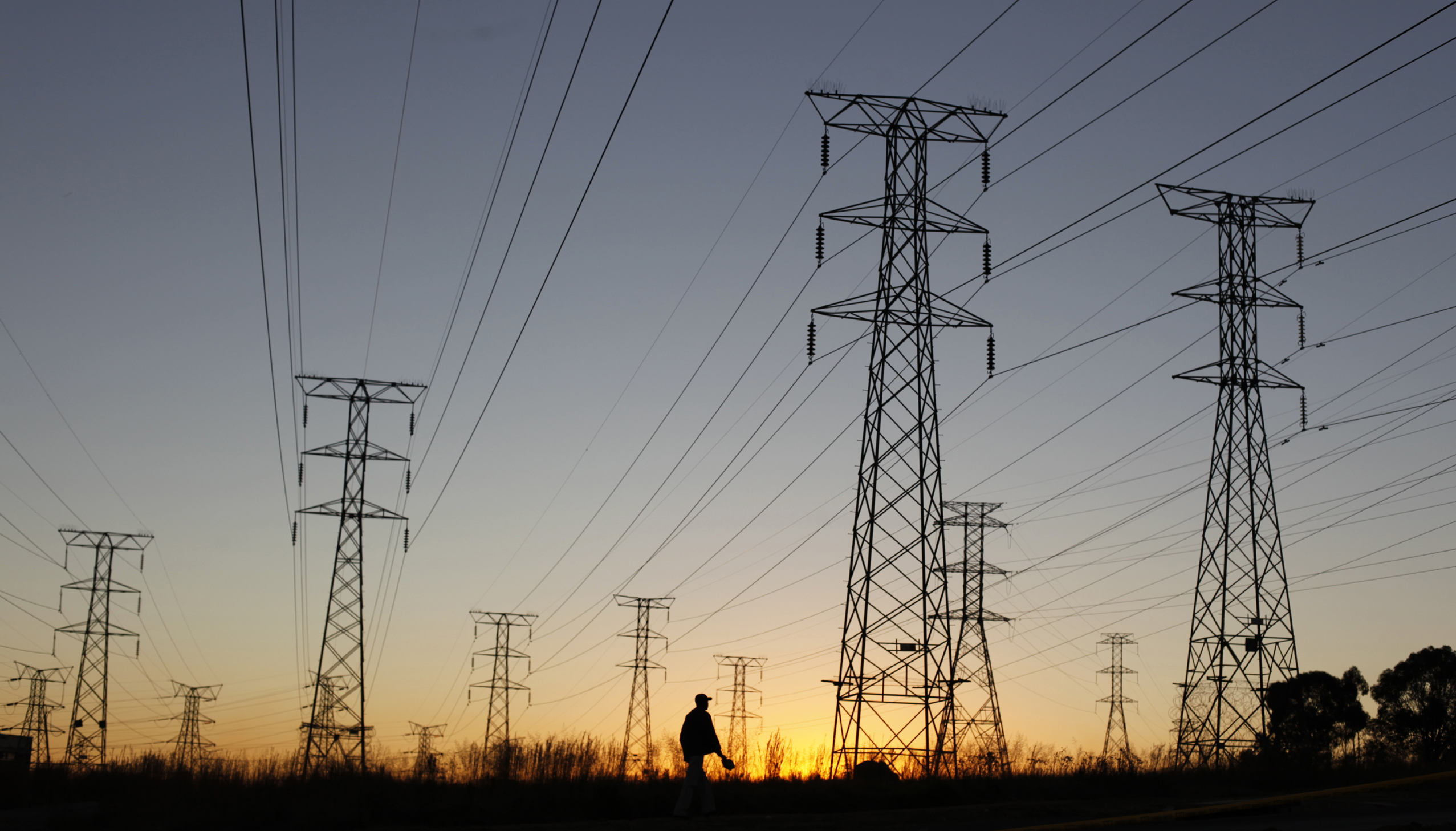 A man walks past electricity pylons as he returns from work in Soweto, outside Johannesburg